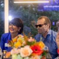 Group of people at a table with GVSU President smiling and looking towards speaker